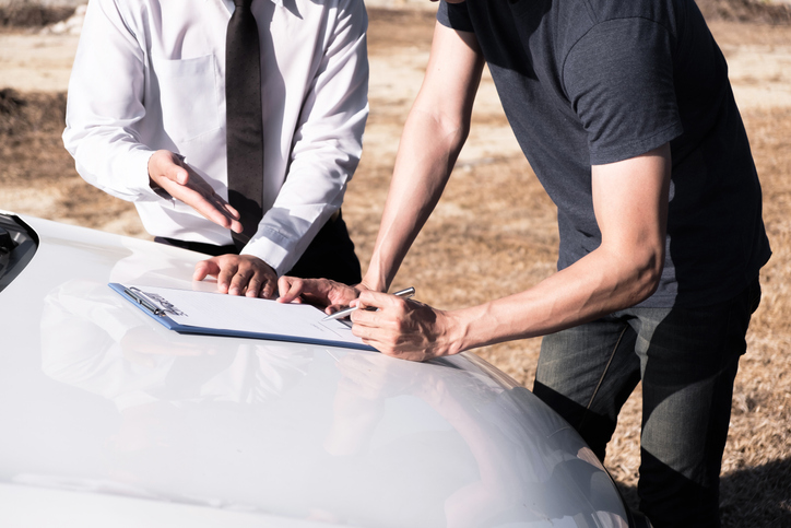 Men exchanging car insurance information and filling out paperwork 