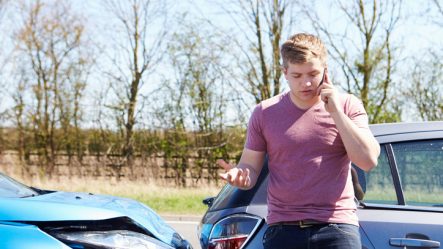 Man talking on the phone to his car insurance after an accident