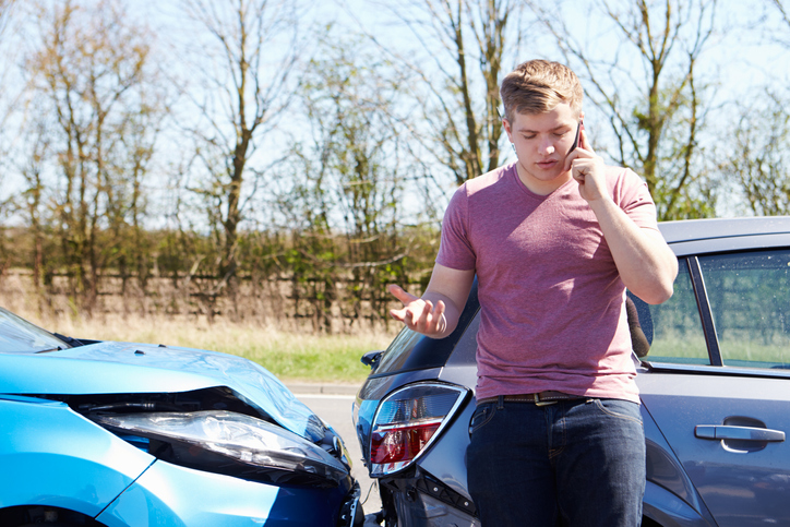Man talking on the phone to his car insurance after an accident